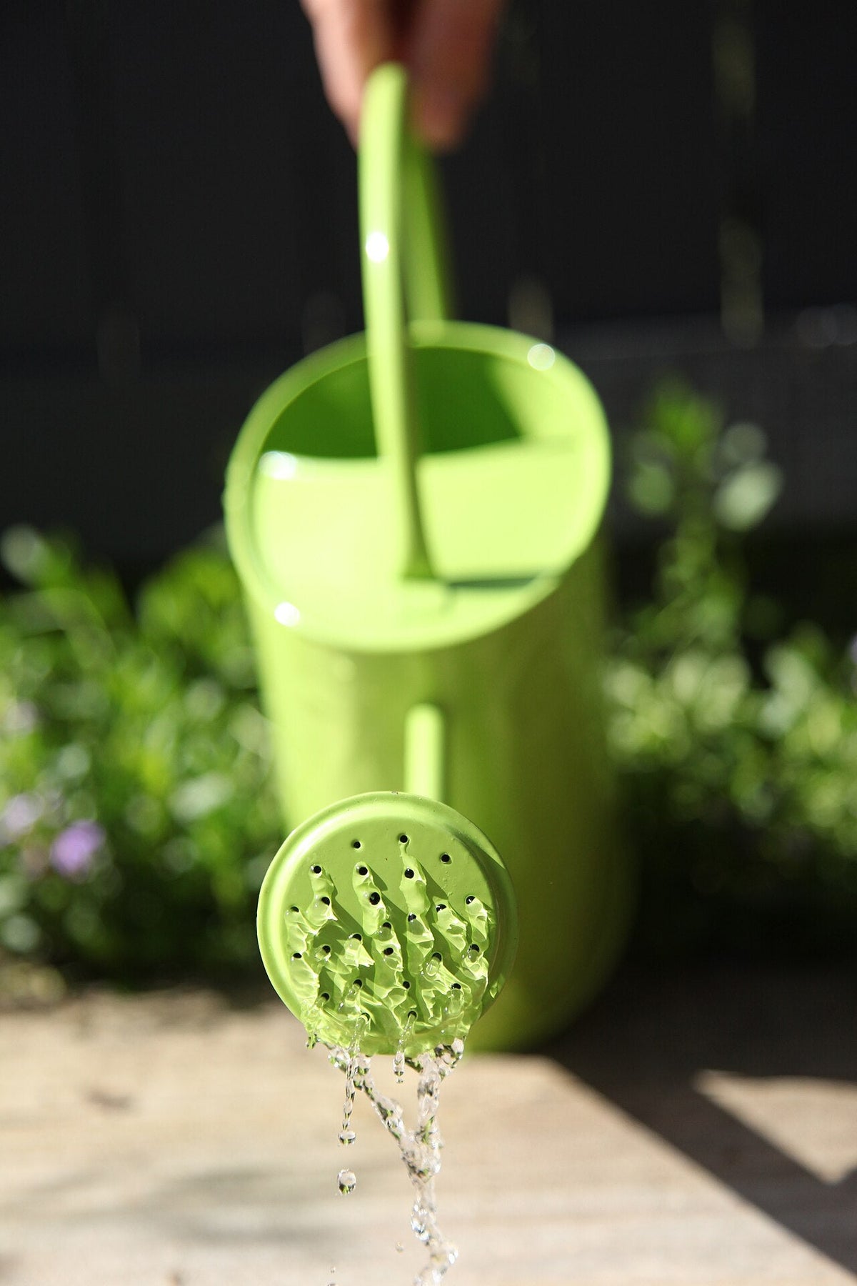A green watering can standing in a garden